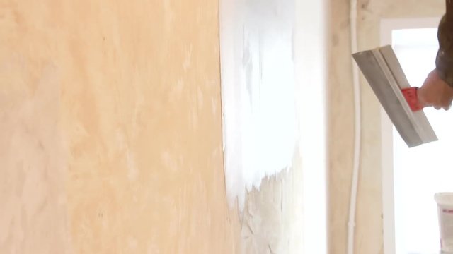 Man plastering wall with spatula
