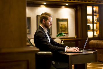 Young man working on a laptop in the room with antique furniture