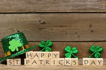 Happy St Patricks Day wooden blocks with shiny shamrocks and leprechaun hat on a wooden background