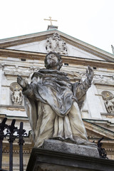 Fototapeta premium Statue of saint on the background of a medieval church with a cr