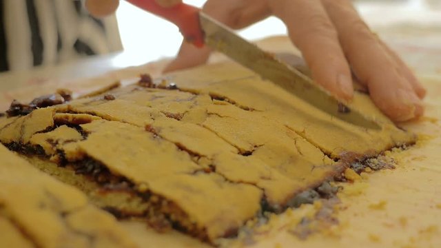 married woman cut into slices a homemade strudel on wooden cutting board