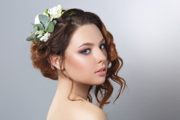 Beauty fashion portrait of a beautiful girl with a natural make-up and hairstyle curls isolated on a gray background.