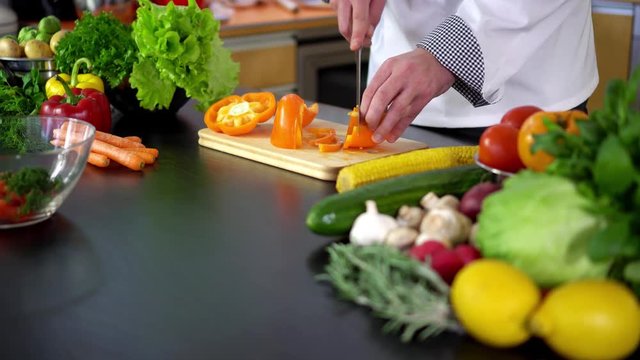 vegetable salad - chef cutting paprika on board in kitchen