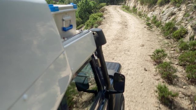a shot from a camera attached to the side of an off road campervan driving on rough tracks in sardinia, italy