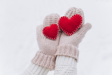 Girl in mittens holding heart on Valentine's day in winter outdoors