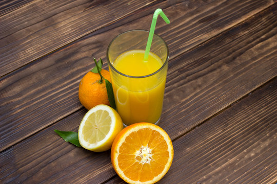 lemon juice and orange in the glass. Composition on wooden background. Fruit mix