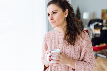 Beautiful young woman drinking coffee at home.