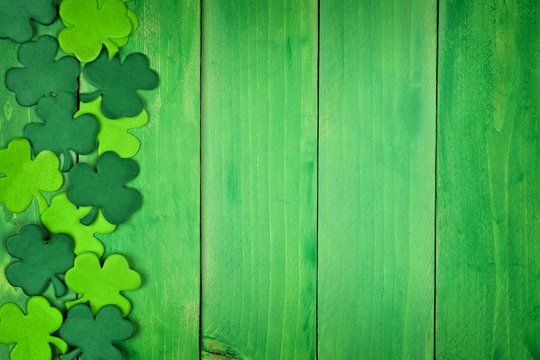 St Patricks Day side border of paper shamrocks over a green wood background
