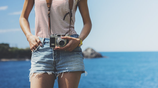 Tourist traveler photographer taking pictures seascape on vintage photo camera on background piar, hipster girl enjoying nature holiday, mockup ocean waves view, blurred backdrop