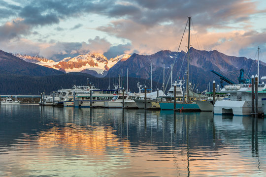 Boats at a pier in Seward with mountains in background. Seward's Boat Harbor is situated on the northern edge of Resurrection Bay.