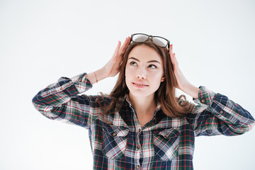 Happy cute young woman in glasses standing and looking away