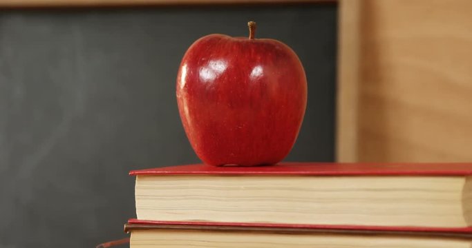 Close-up of books stack with red apple on a desk 4k