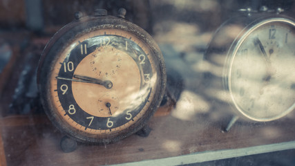 Vintage grunge alarm clock on a display cabinet.
