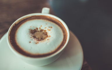 A cup of hot cappuccino coffee add brown sugar in a vintage style.
