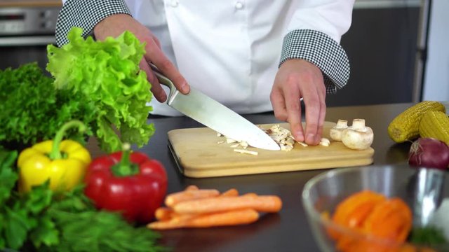chef chopping champignon on wooden board for food cooking in kitchen