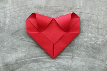 one folding red paper heart on cement wall for valentine pattern