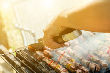 Young man cooking meat on barbecue in house backyard