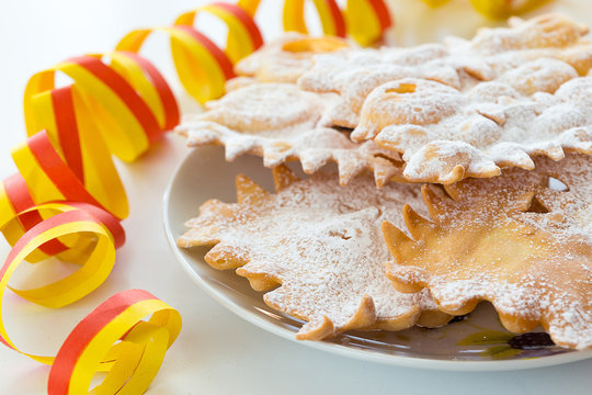 Chiacchere di carnevale e stelle filanti su tavolo bianco