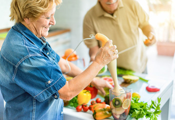 Senior couple cooking healthy vegetarian meal with fruits and vegetables