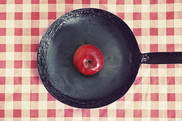 Frying pan with red apple concept 
