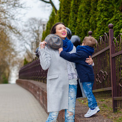 Portrait of fashionable baby boy and his gorgeous mother among balloons. little boy hugs his mother emotionally.