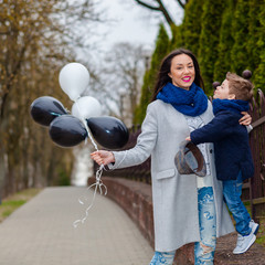 Portrait of fashionable baby boy and his gorgeous mother among balloons. little boy hugs his mother emotionally.