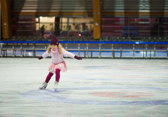 Pretty girl skates in a red cap, warm gloves and sweater