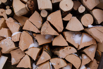 Background of dry chopped firewood logs pile with snow