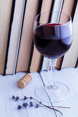 Books, glass of red wine on an old wooden table