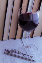 Books, glass of red wine on an old wooden table