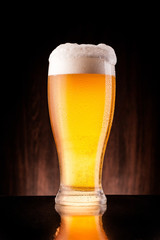 light beer in frosty glass over dark wooden background