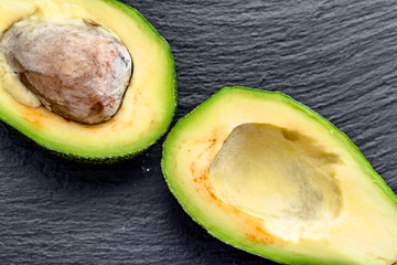 Halves of avocado on black background