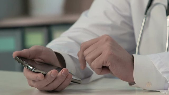Physician's hands sliding files, typing text on smartphone, medical consulting