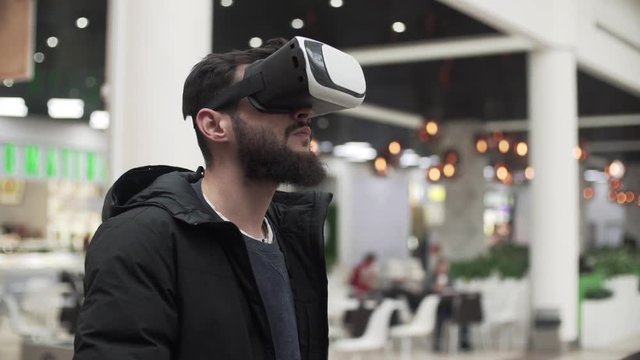 Young Man using virtual reality goggles in shopping center
