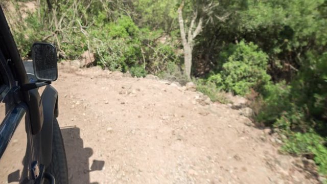 a shot from a camera attached to the side of an off road campervan driving on rough tracks in sardinia, italy
