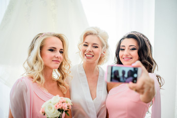 Bridesmaid in pink dress takes selfie on her iPhone posing with