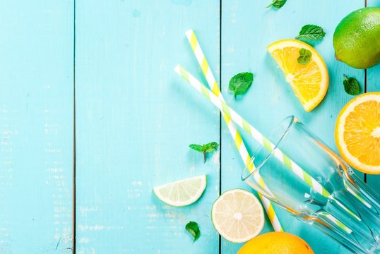 Ingredients For Citrus Juice Or A Refreshing Summer Cocktail: Orange, Lime, Mint Leaves, Along With A Glass And Drinking Straws, Top View, Copy Space