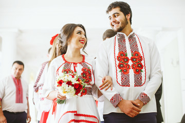 Obraz premium Lovely newlyweds in embroidered shirts look at each other before