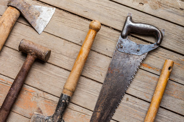 Old rustic tools on wooden texture background. Flat lay with ax, sledgehammer, shovel, saw, rake. Top view close-up