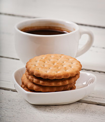 Cup of coffee and delicious baked cookies on old wooden background.