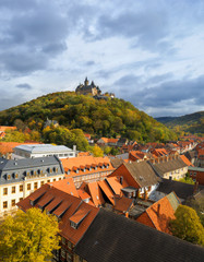 A top view over Wernigerode town with a medievel castle crowning the hill top. Wide angle picture taken from the top of a town church on a cloudy Autumn day