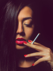 Portrait of the beautiful elegant girl smoking cigarette on black background.