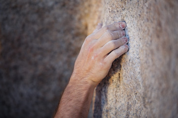 Close up of a young man's hand covered in chalk while rock climbing - obrazy, fototapety, plakaty