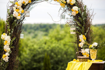 Wedding altar made of osier, yellow and white flowers stands on