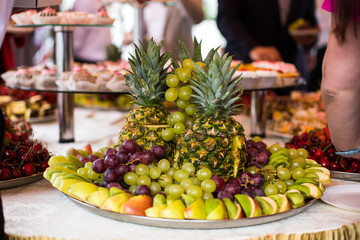 Cut ananases stand on rich served dinner plate with grape, kiwi