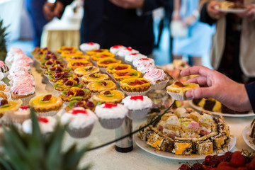 Man takes backed basket from large plate with sweets