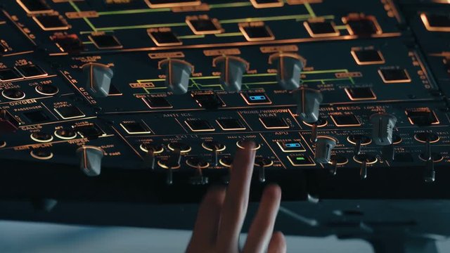 Close shot of overhead panel of modern aircraft with captain's hand switching control buttons and knobs. Interior of Airbus A319 A320 A321