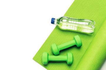 Fitness concept - green yoga mat and dumbbells