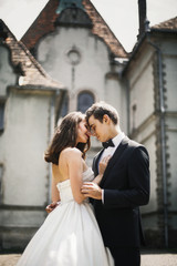 Fototapeta premium Handsome groom holds bride tender in his arms standing before ol