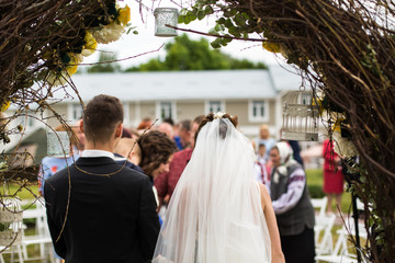Look from behind at wedding altar decorated with bird cages and